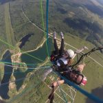 Параплан в тандеме летит над полями и озером в Санкт-Петербурге