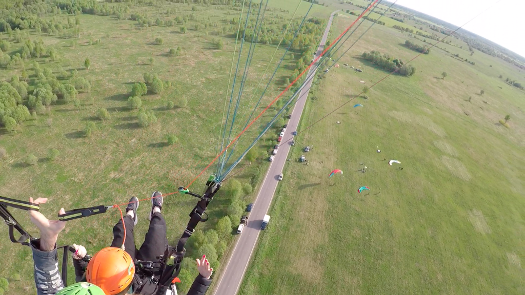 Полет в тандеме на параплане над дорогой и стартовой площадкой