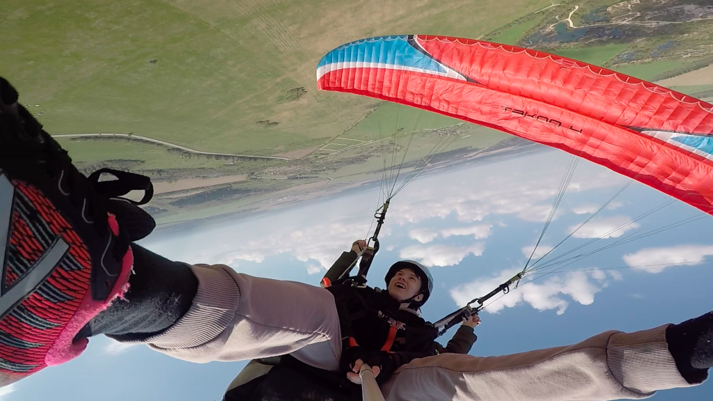 Два парапланериста в тандеме с радостью исполняют спиральный маневр, быстро спускаясь вниз.