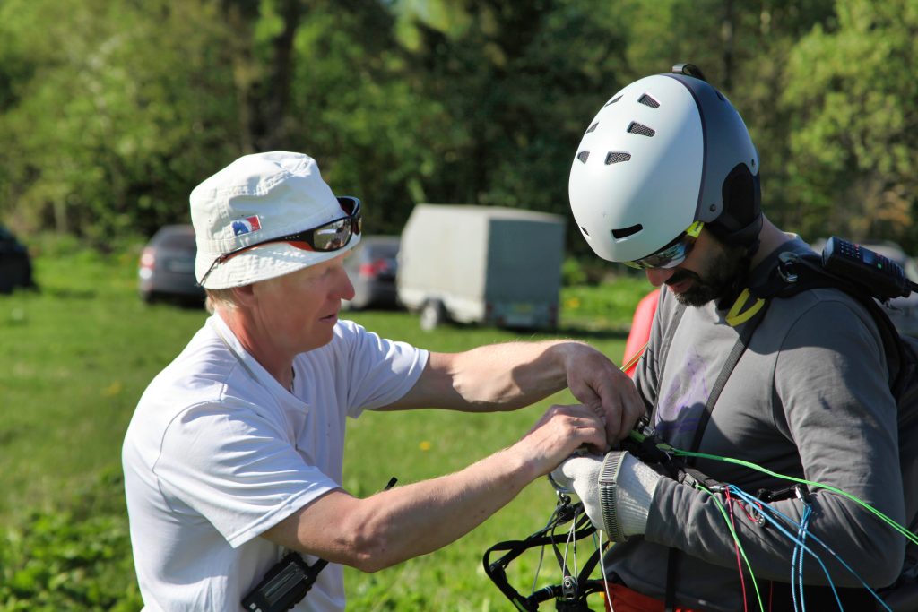 Пилот-инструктор проверяет наличие запасного парашюта у ученика перед полётом.
