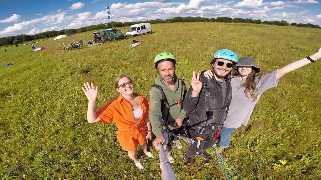 Парапланерист парит над зелёными полями в окрестностях Санкт-Петербурга.